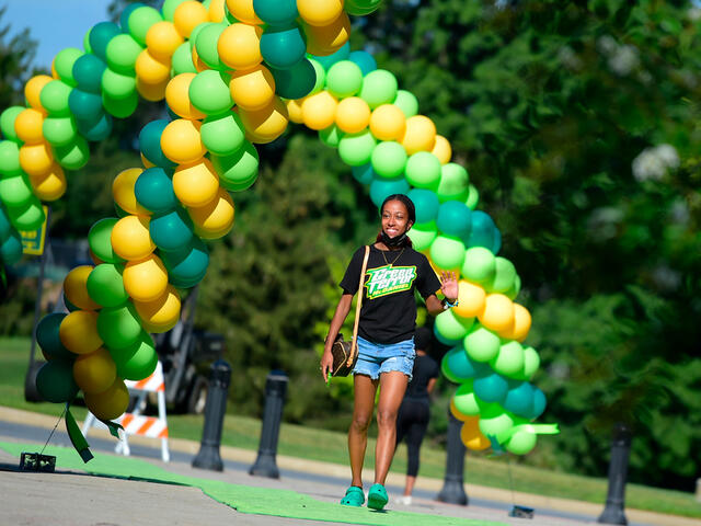 student walks under balloon arch